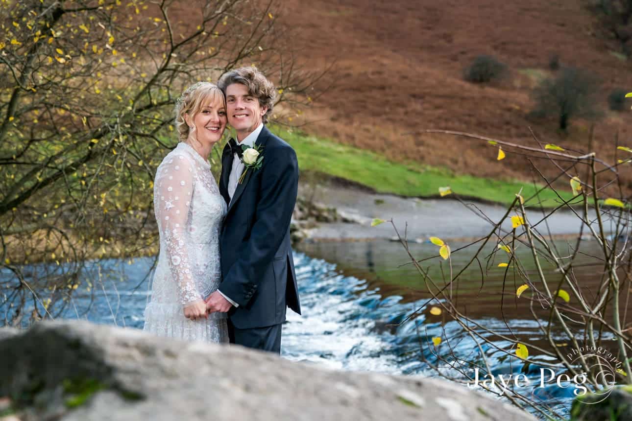 a bride and groom photographed by the river rothay at grasmere