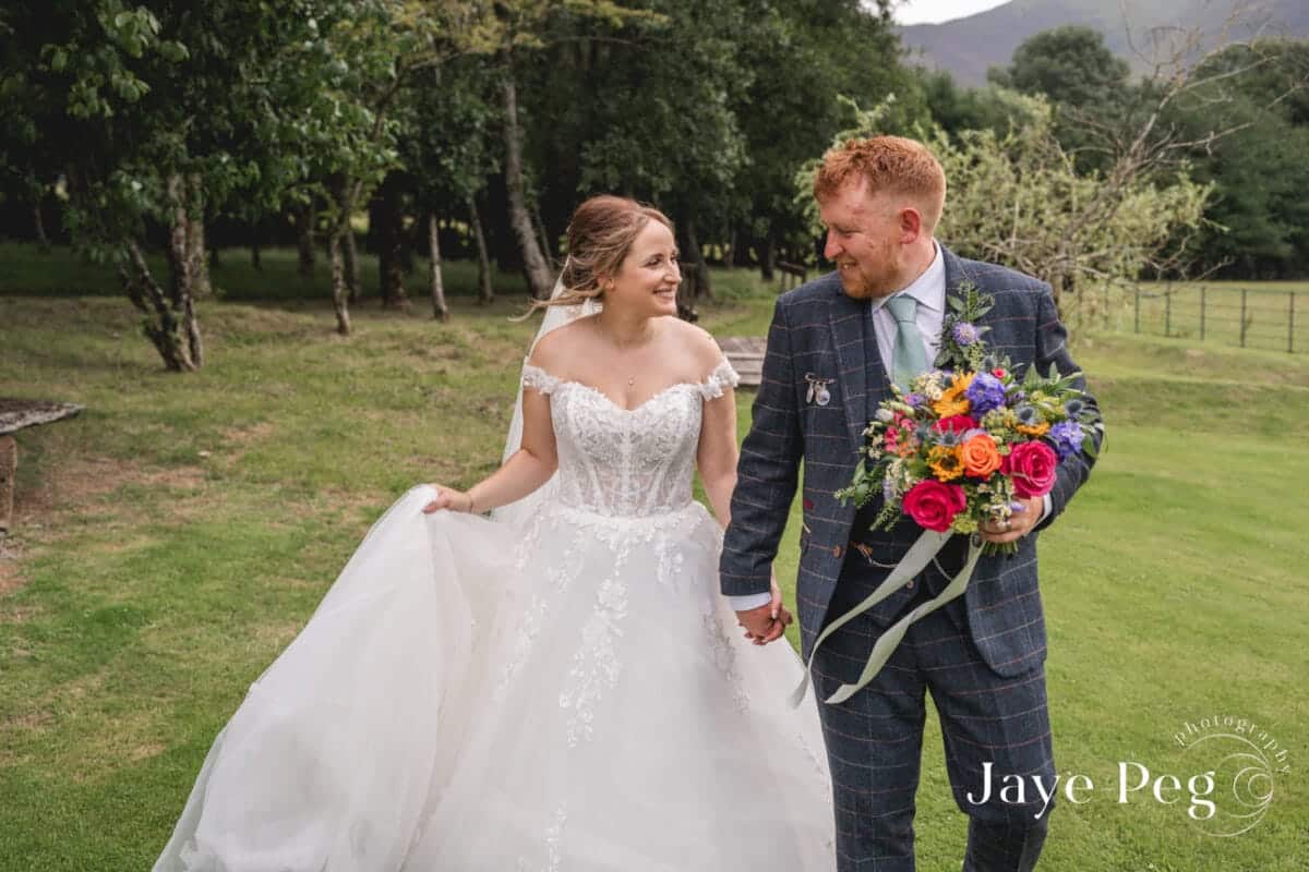 a relaxed photo of a bride and groom walking through the grounds of new house farm on their wedding day