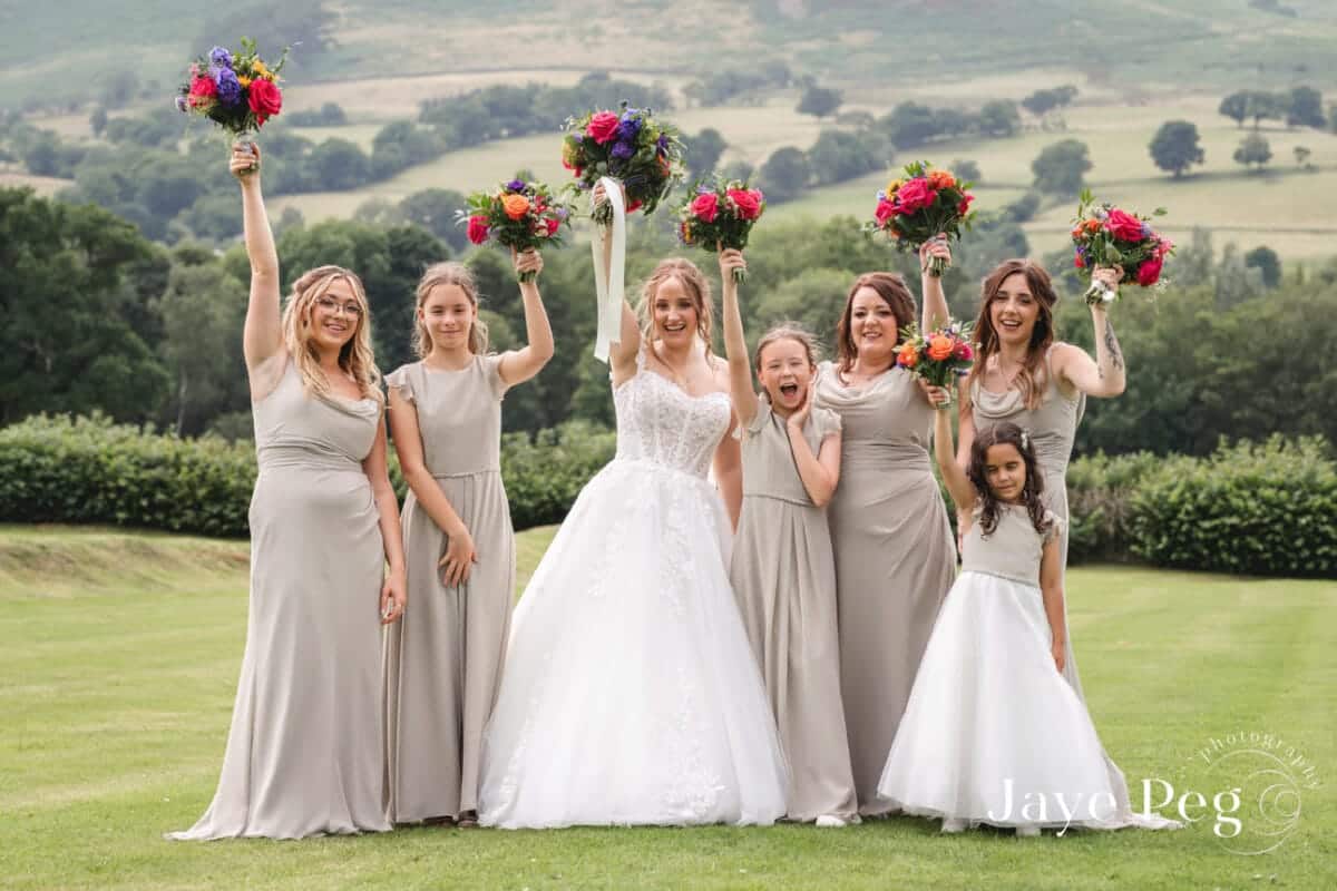 a bridal party hold their bouquets in the air