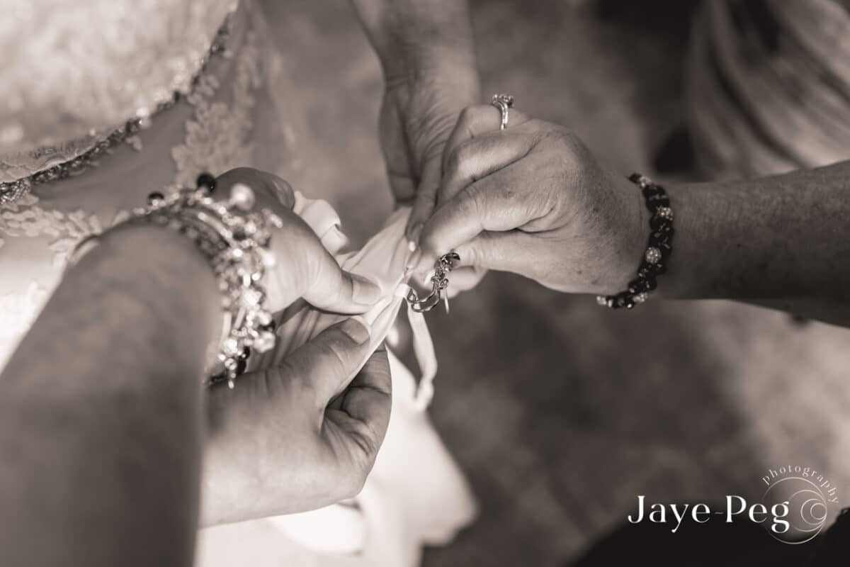 Hands fastening a bracelet, sepia wedding preparation image