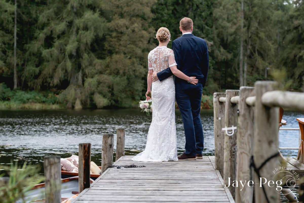 a bride and groom looking out cross knipe tarn at gilpin lake house
