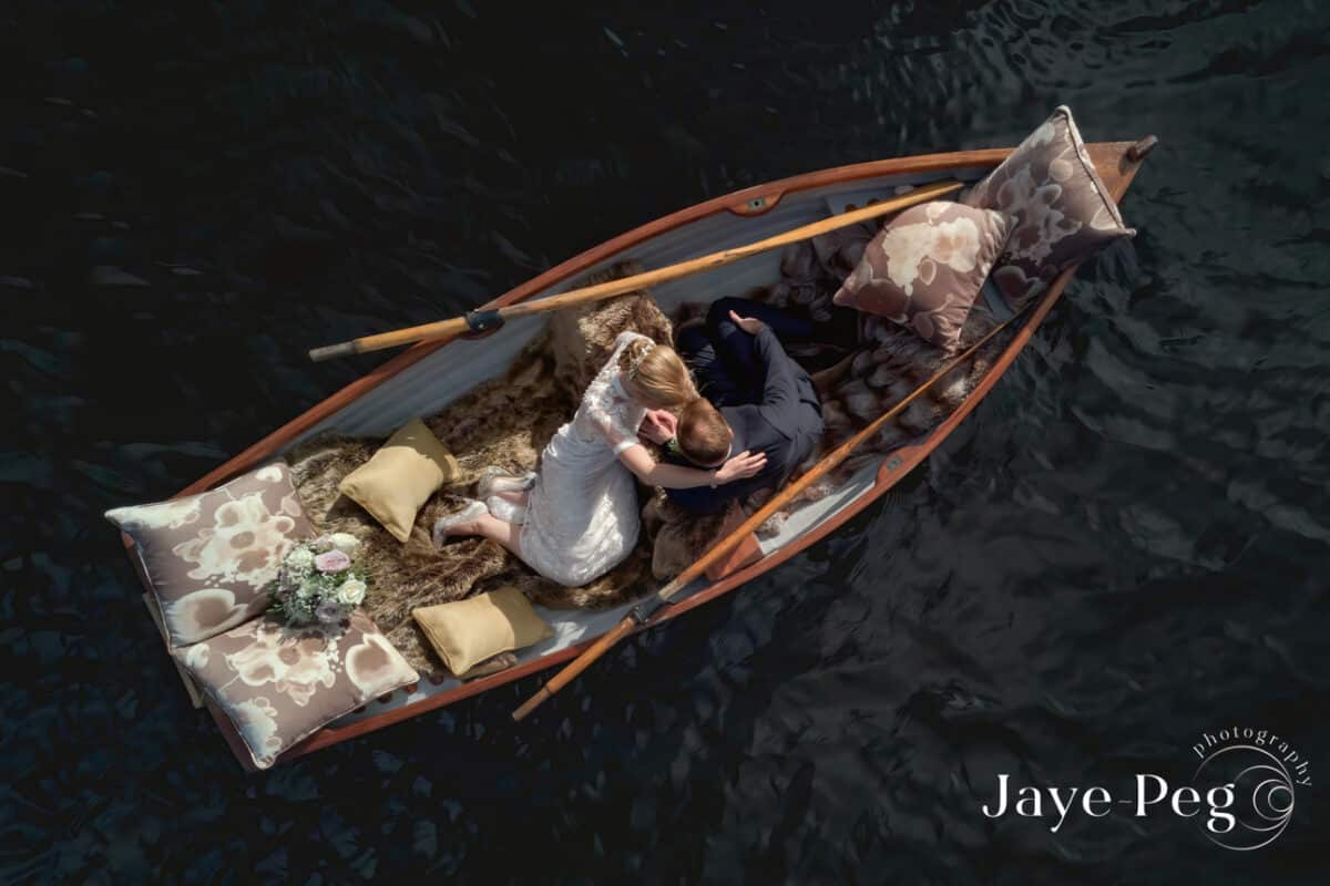 a drone photograph of a bride and groom in a boat on knipe tarn at gilpin lake house