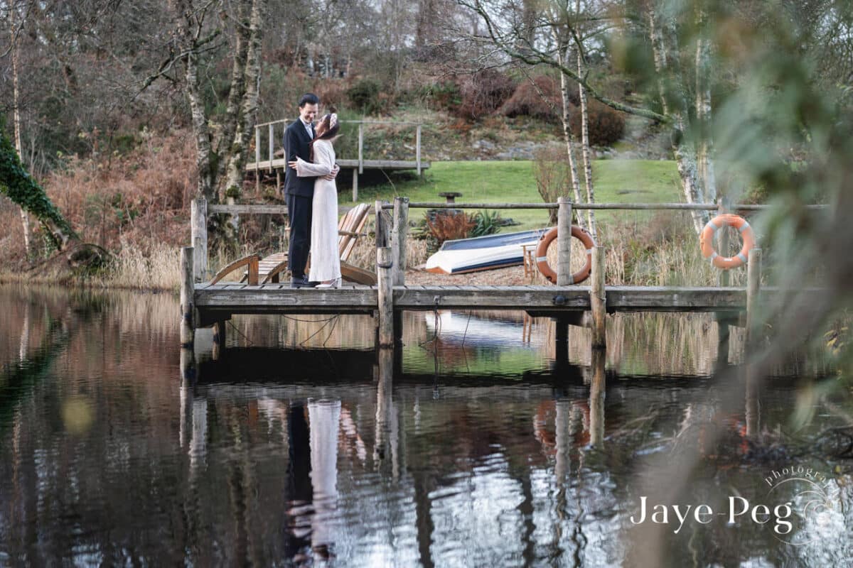 a bride and groom on the jetty over knipe tarn at gilpin lake house