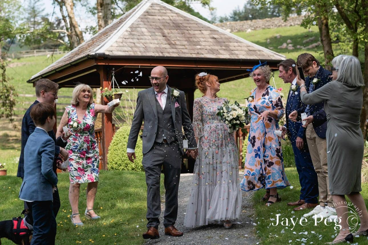 a bride and groom have confetti thrown over them by their wedding guests after their ceremony at briery wood country house hotel