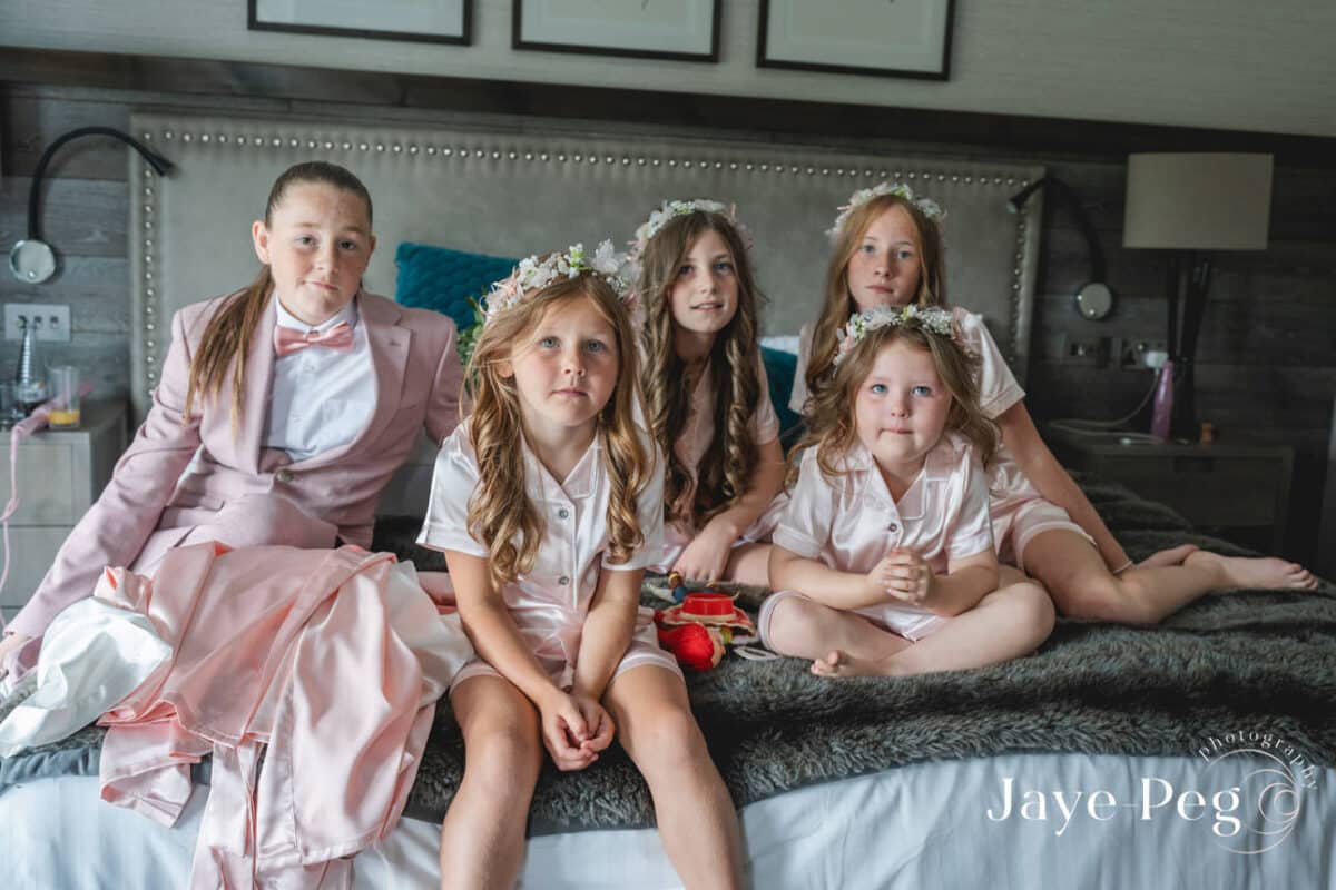 Children in wedding attire sitting on bed