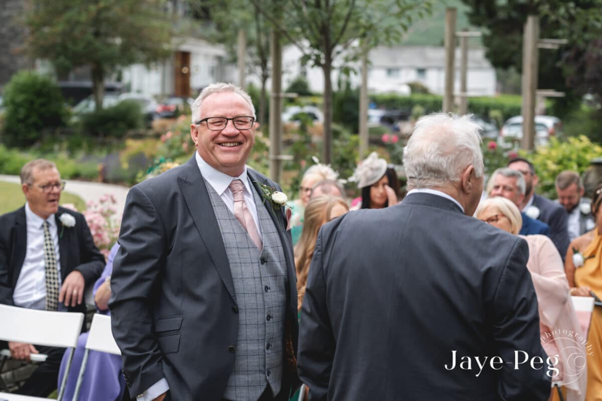 Smiling man at outdoor wedding ceremony.