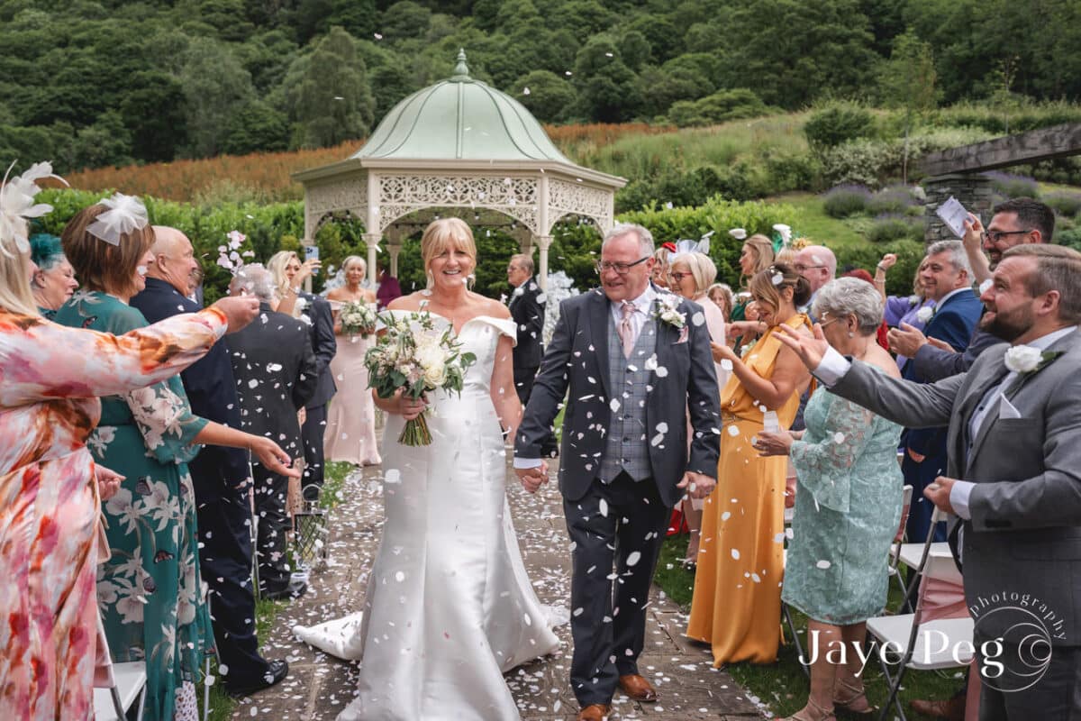 Joyful wedding confetti toss outdoors with smiling couple.