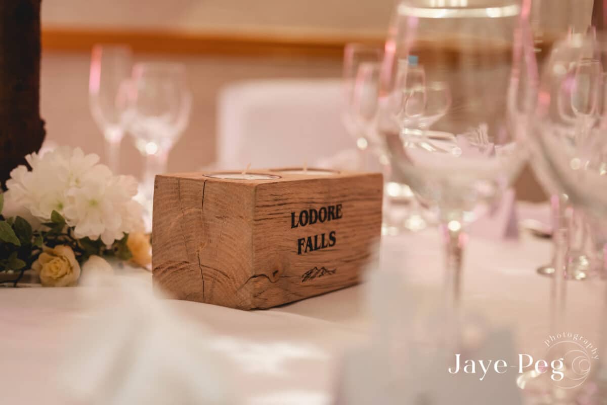 Rustic candle holder centerpiece with white flowers at event.