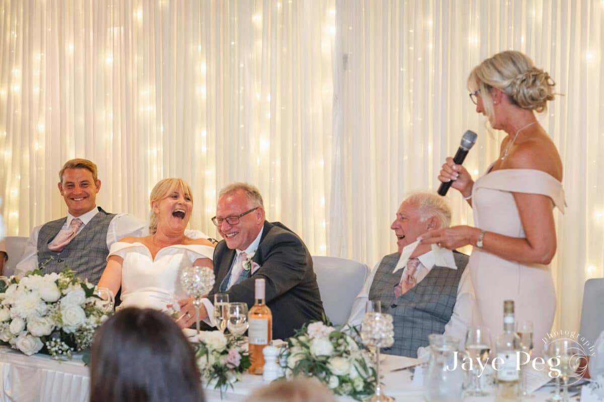 Woman giving speech at joyful wedding reception.