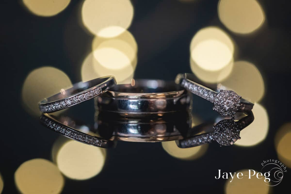Sparkling wedding rings with golden bokeh background.