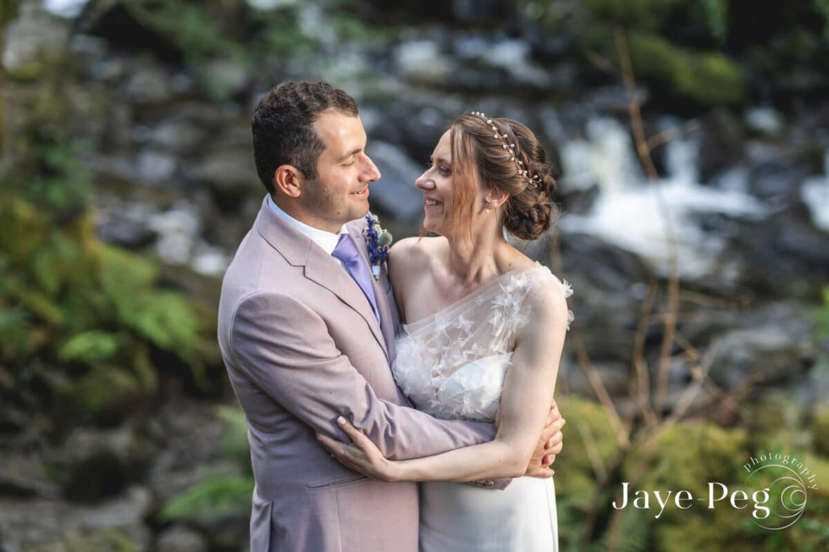 Couple embracing at wedding near waterfall