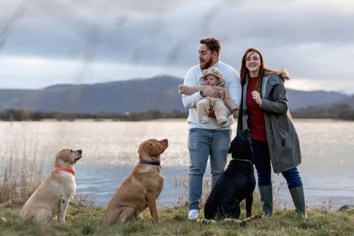 a family with their three dogs on the shore of bassenthwaite lake