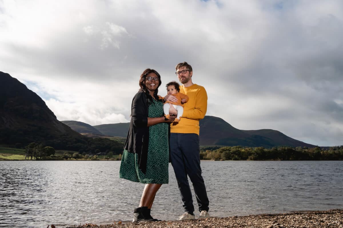 a family photograph on the shore of crummock water with lake district fells behind them