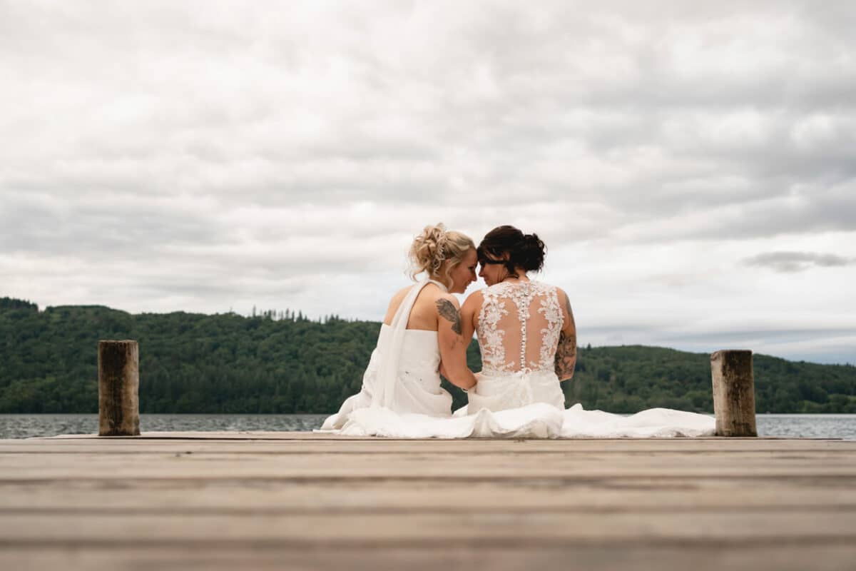 Two brides sitting on a windermere jetty in the lake district
