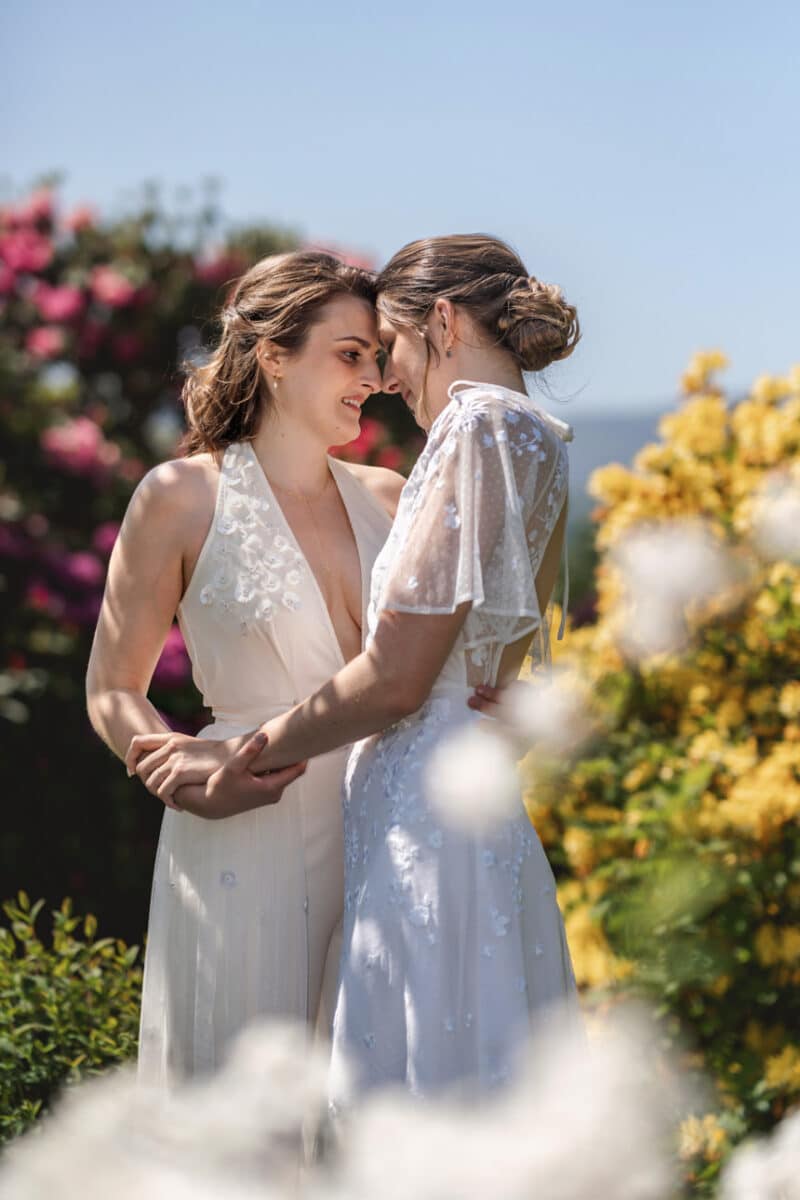 two brides sharing a tender moment in a colourful garden