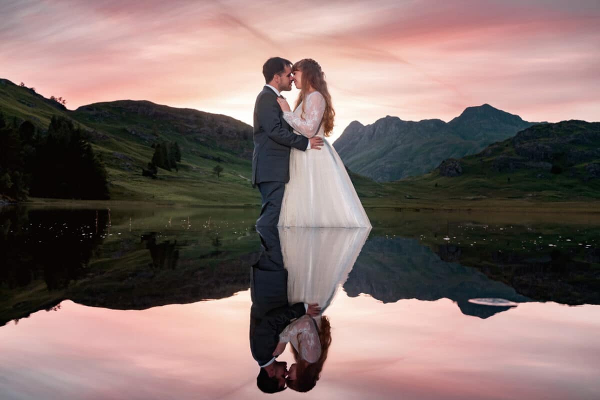 a bride and groom standing in Blea Tarn and reflected in the water