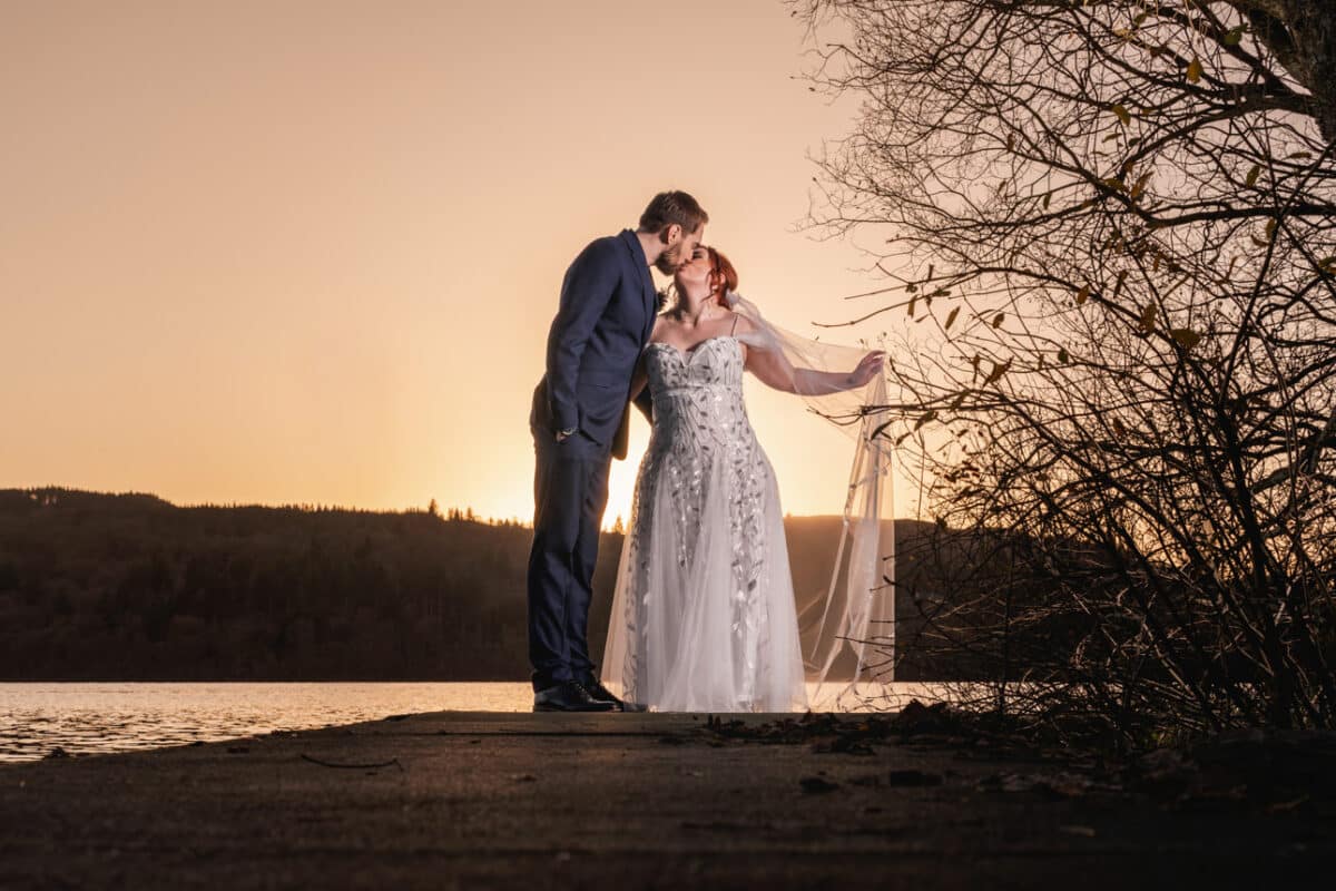 a bride and groom at golden hour beside a lake