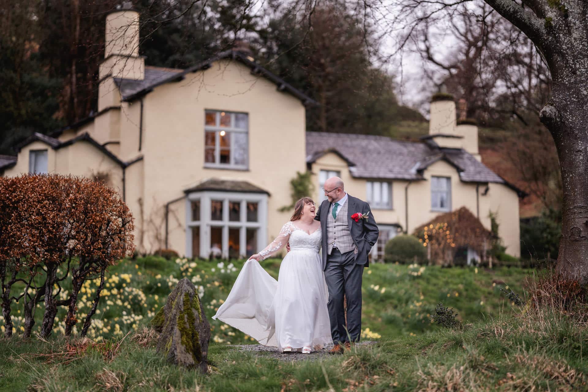 a bride and groom smiling and laughing in front of Lancrigg in Grasmere